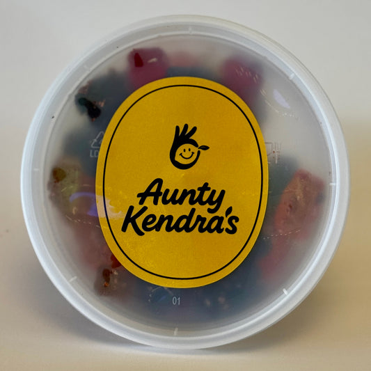 Container of colorful gummy bears with a yellow label reading 'Aunty Kendra's' on a light background.